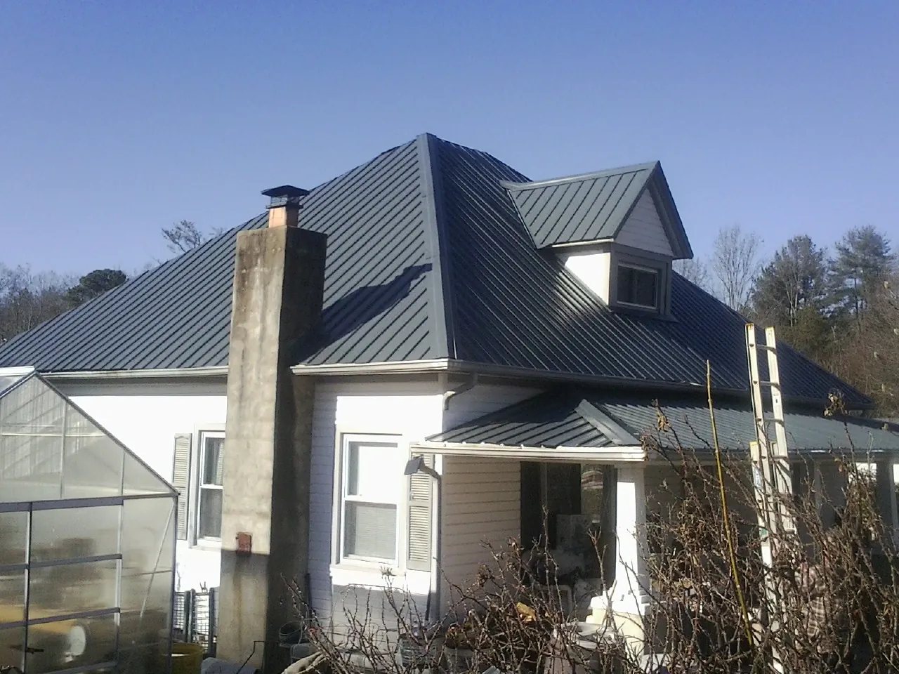 Dark blue standing seam metal roof on a white farmhouse with dormer — Slate & Tile Roof Repair by Roofing Brothers in Kuna
