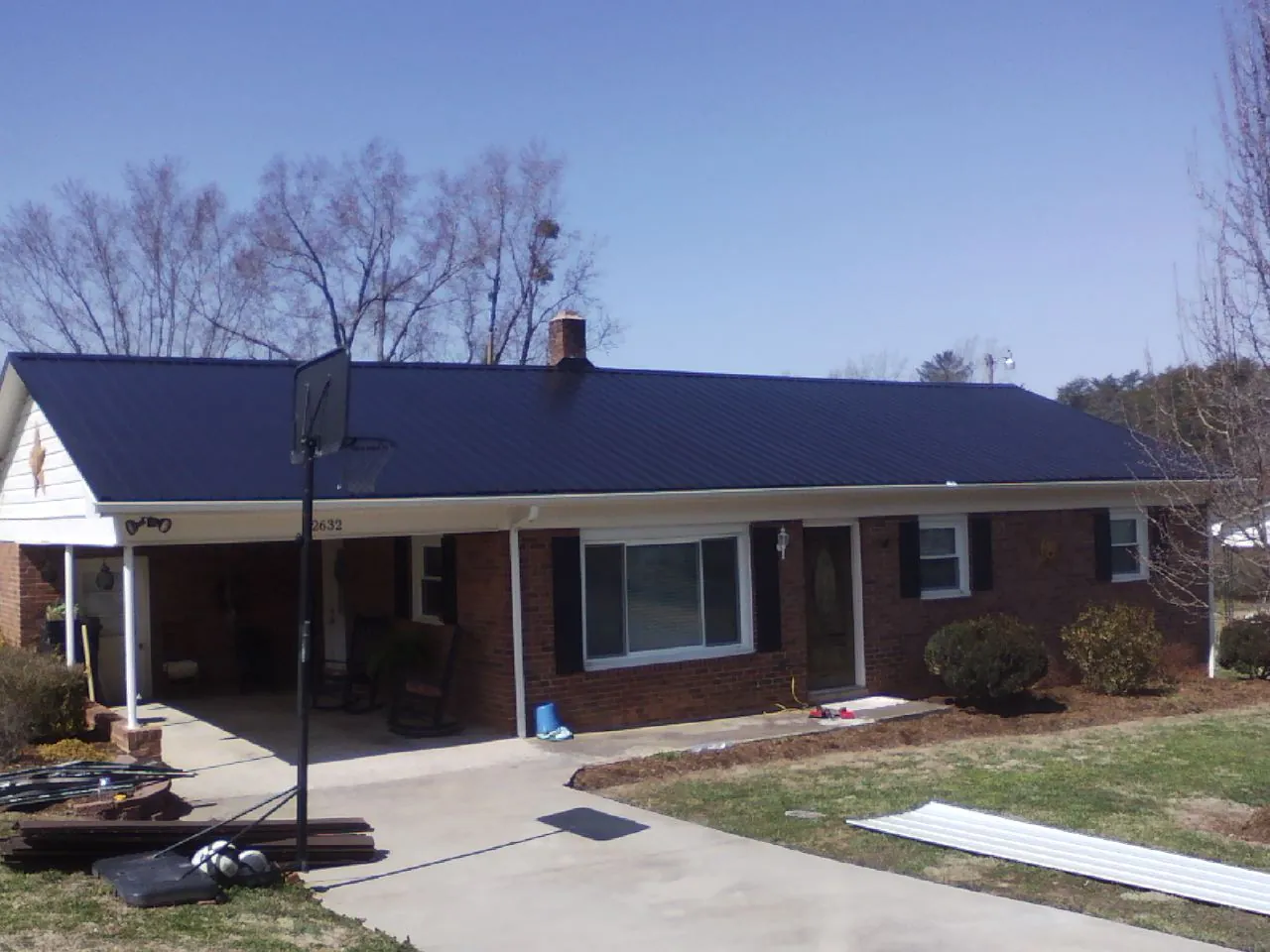 Finished dark blue metal roof on a brick ranch with a carport in Kuna