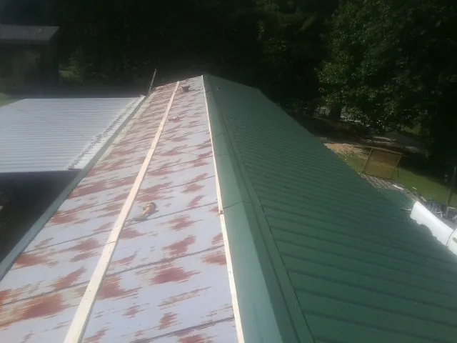 Old rusted panels beside newly installed green metal roofing — Wind Damage Roof Repair by Roofing Brothers in Kuna