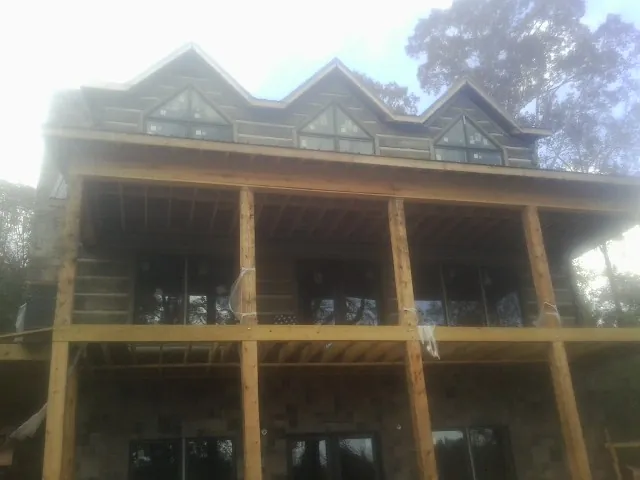 Dormers and porch framing on a large log home under construction — Roof Coating work by our crew in Kuna