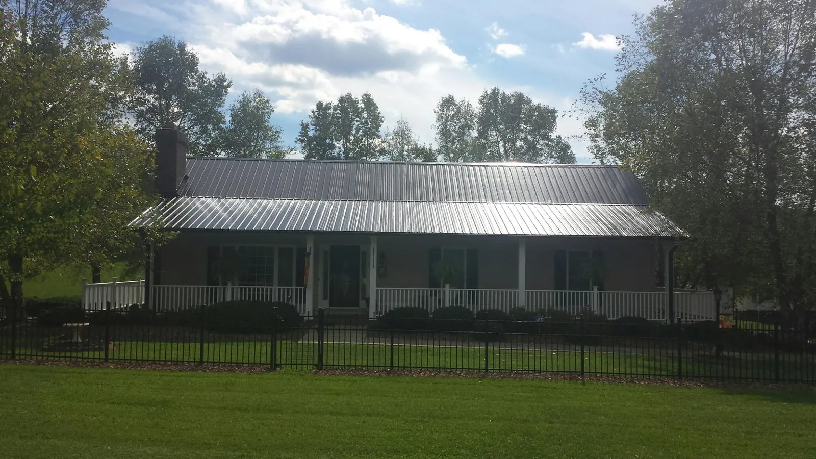 Gray metal roof on a brick ranch with a full width front porch — Gutter Guard Installation work by our crew in Kuna