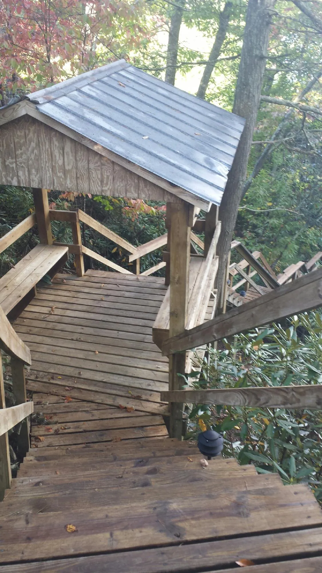 Metal roofed shelter over wooden steps on a wooded walkway — Skylight Repair & Installation work by our crew in Kuna