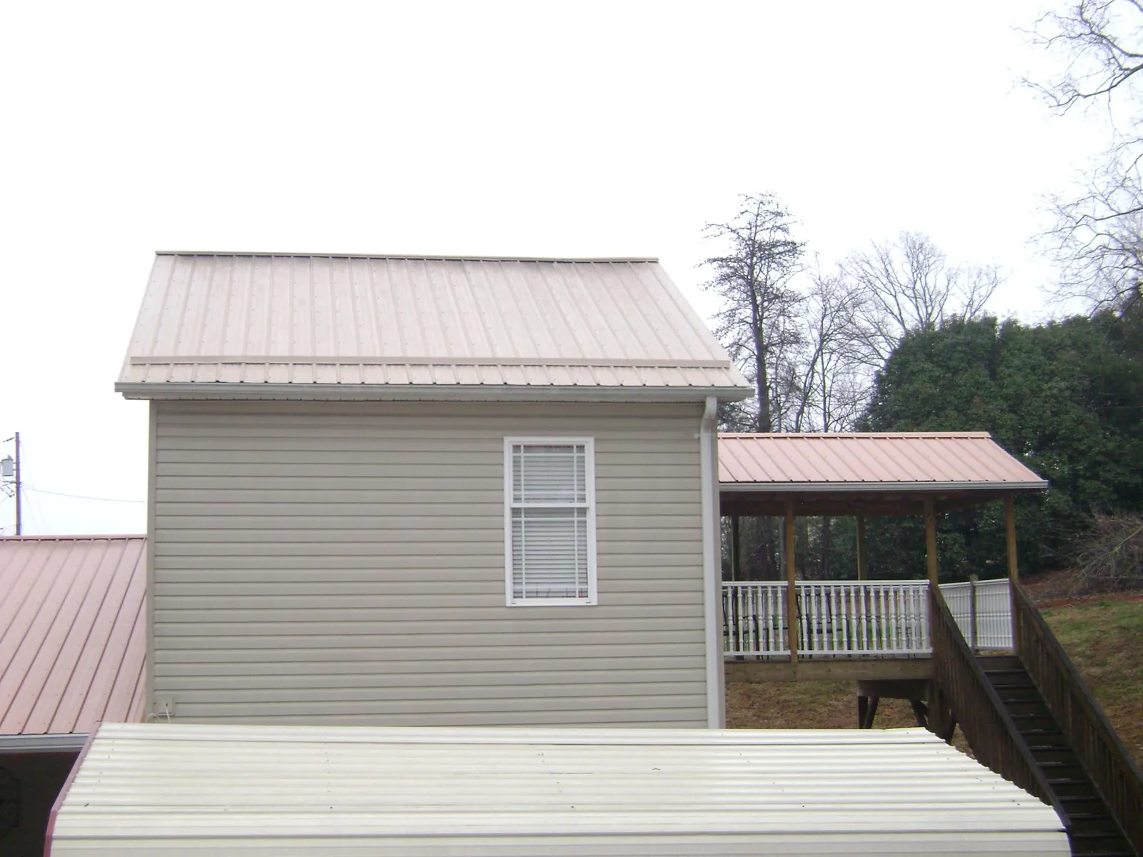 Tan metal roofs on a two story addition and attached porch, from a Roof Replacement job in Kuna