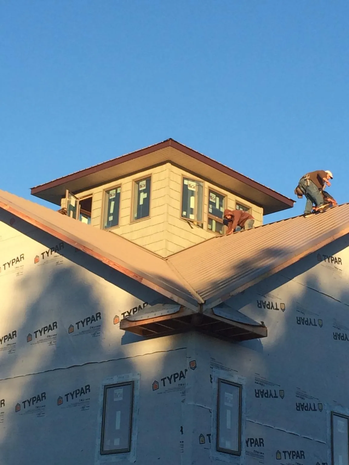 Roofers working around a rooftop cupola on a new metal roof at sunset — Roof Waterproofing in Kuna by Roofing Brothers